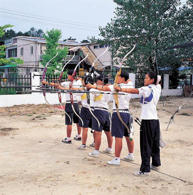학교 운동장에서 양궁 연습을 하고 있는 학생들 이미지